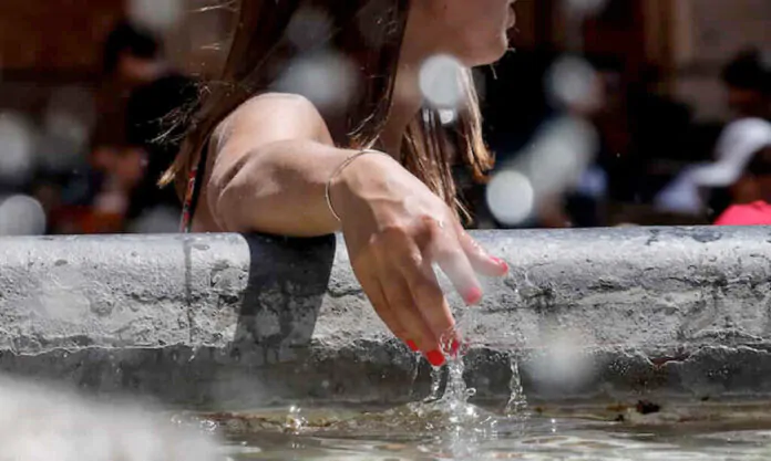 meteo, temperature fino a 40 gradi, ragazza si bagna le mani nella fontana