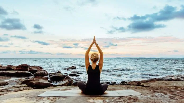 yoga, donna lo pratica in spiaggia