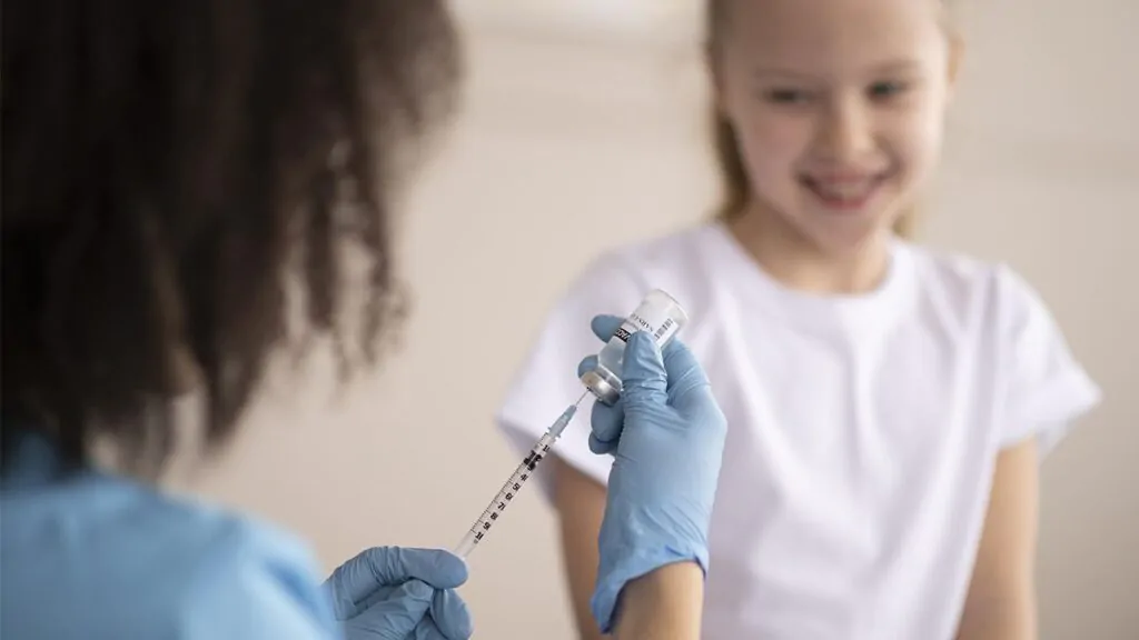 bambina in età scolare attende di essere vaccinata